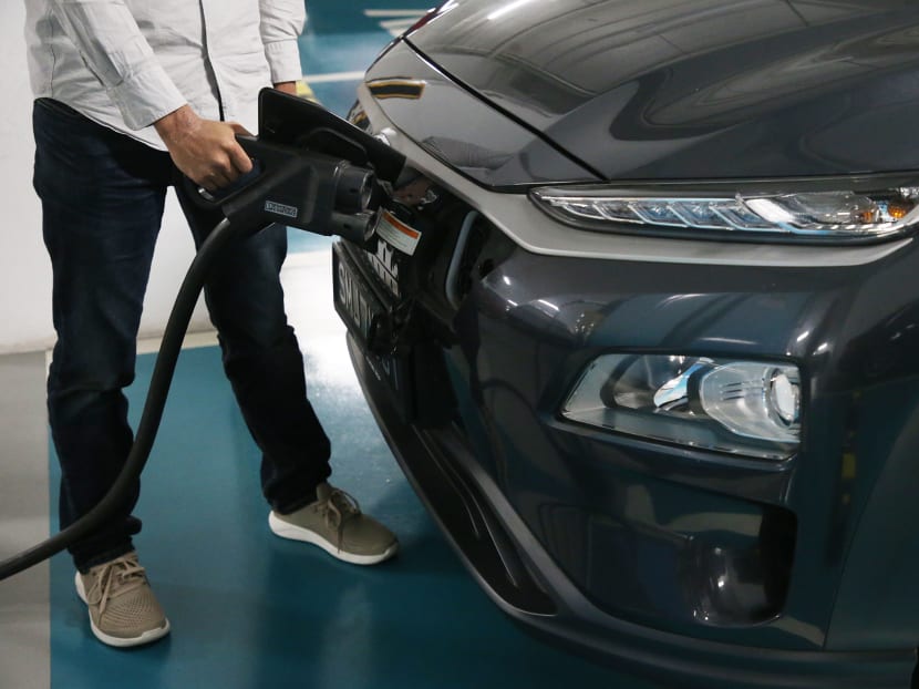 An electric vehicle owner charging his car at a charging station located in a carpark in 2021.