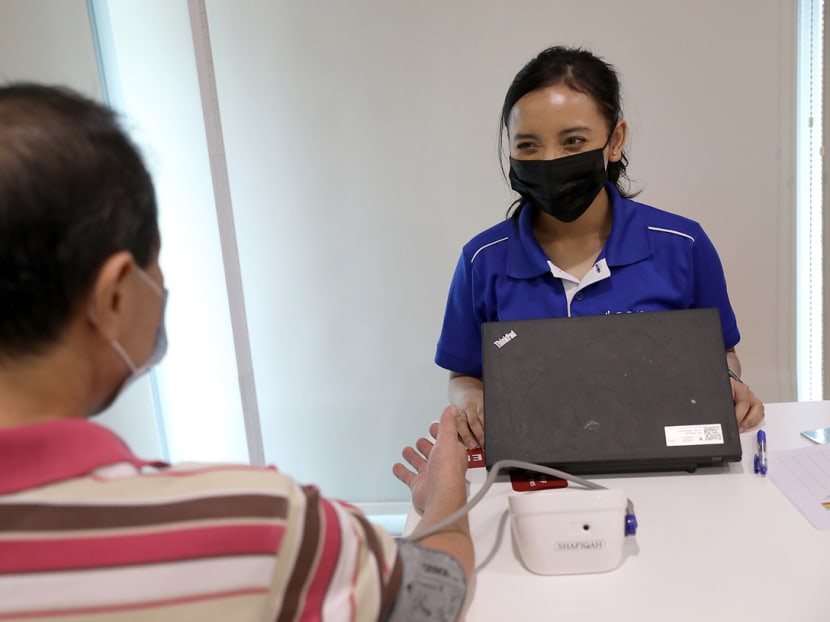 Ms Nurul Shafiqah, Tan Tock Seng Hospital's health coach, checking the blood pressure of a resident in the community she serves.