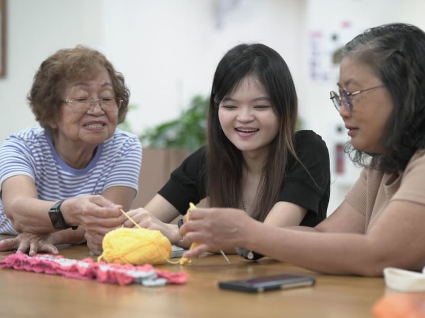 Miss Bridget Ho (centre), an undergraduate with the National University of Singapore, learning crocheting with seniors at an NTUC Health Active Ageing Centre.