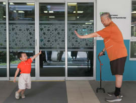 Mr See Keng Soy giving a high-five to three-year-old Darius Huin outside the NTUC Health Day Centre for Seniors in Boon Lay on June 27, 2024.