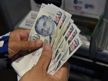 A man withdrawing Singapore dollars from a bank teller machine.