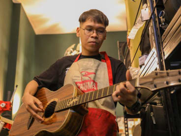 Mr Hazieq Nizam, 25, strumming a guitar he handmade with his teacher, in his guitar studio at Upper Bukit Timah on May 29, 2024.