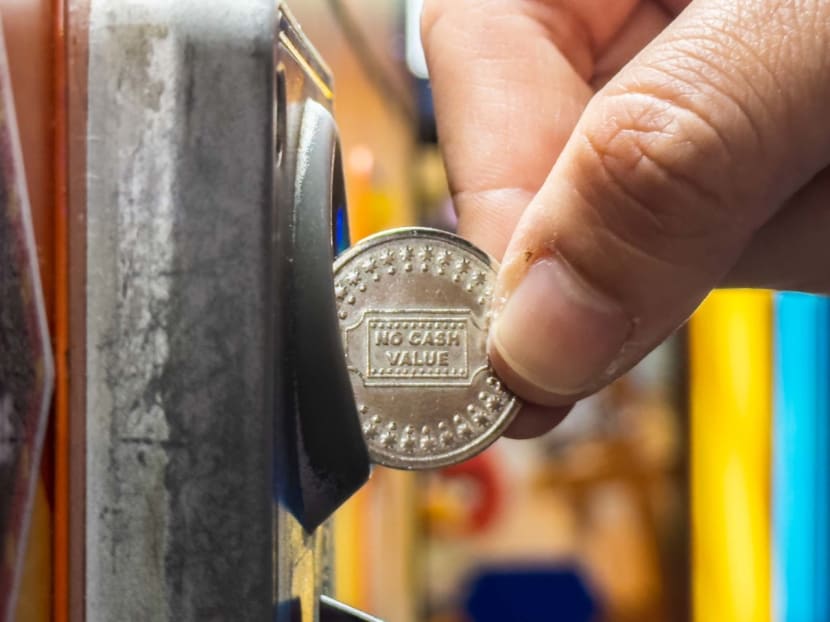 A patron playing a "coin-pusher machine" at a games arcade.